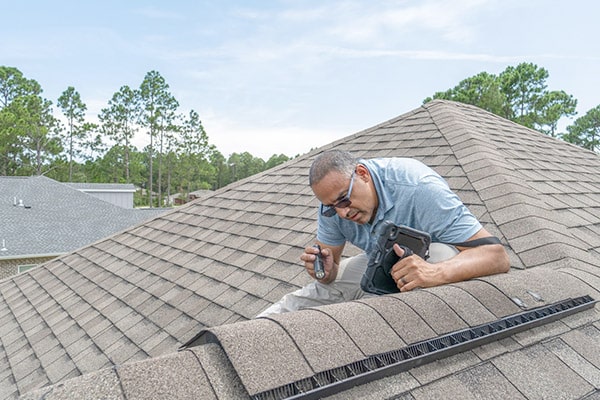 inspector looking at shingles on escambia county home rooftop