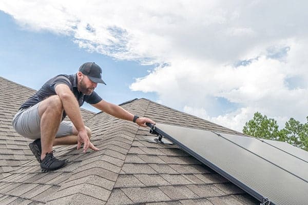 roof inspector looking at solar panels on pensacola home rooftop